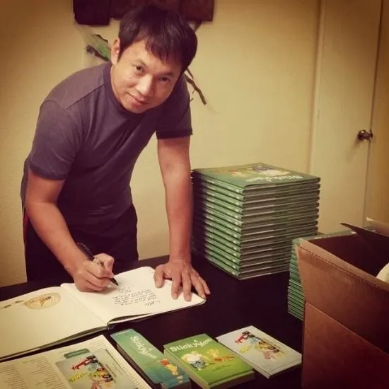 Man signing a book at a table stacked with copies of A Sticky Mess